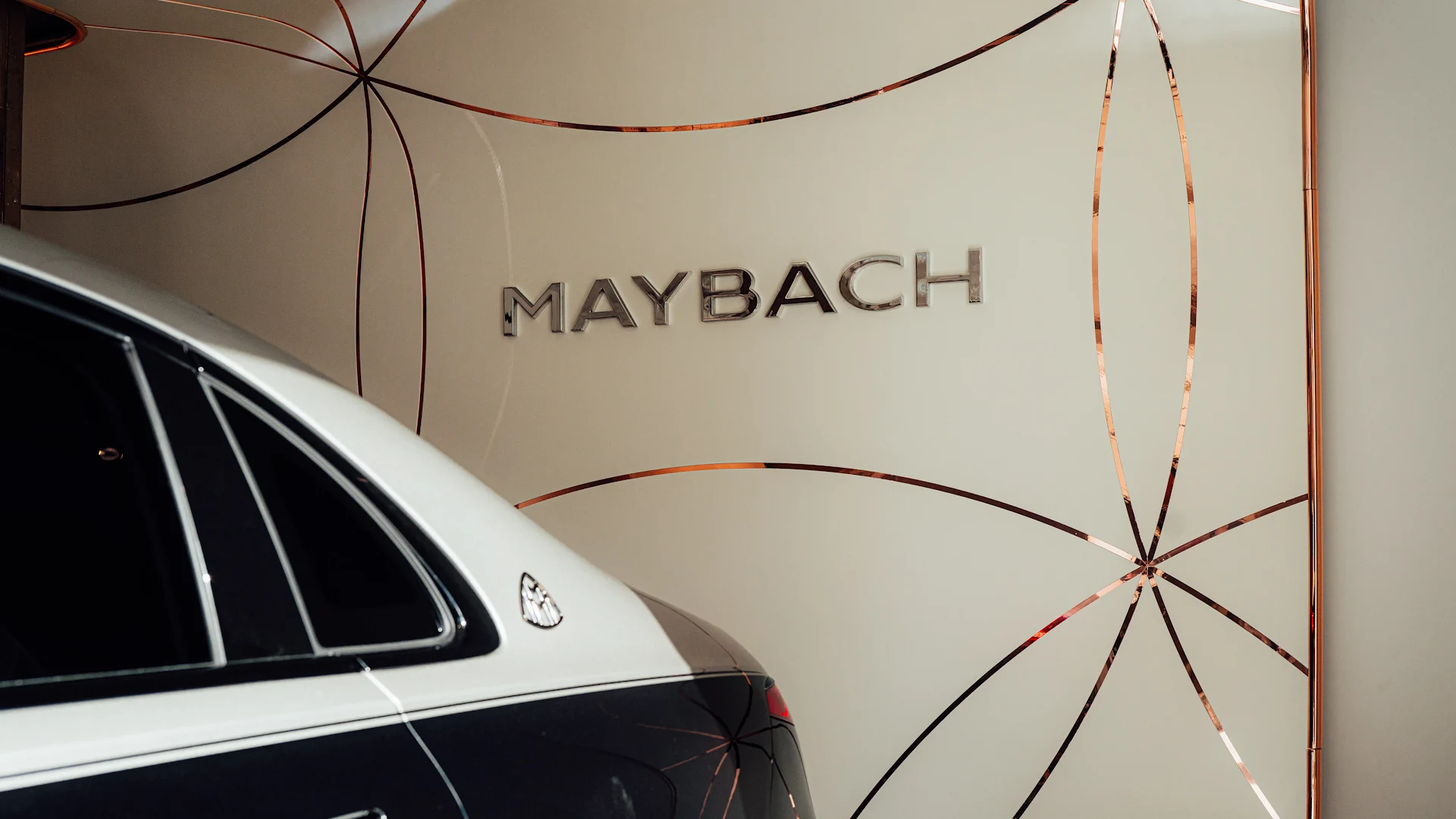 Logo Maybach na ścianie salonu o raz słupku C Mercedesa-Maybacha S580 stojącego w Atelier Maybach w Warszawie
