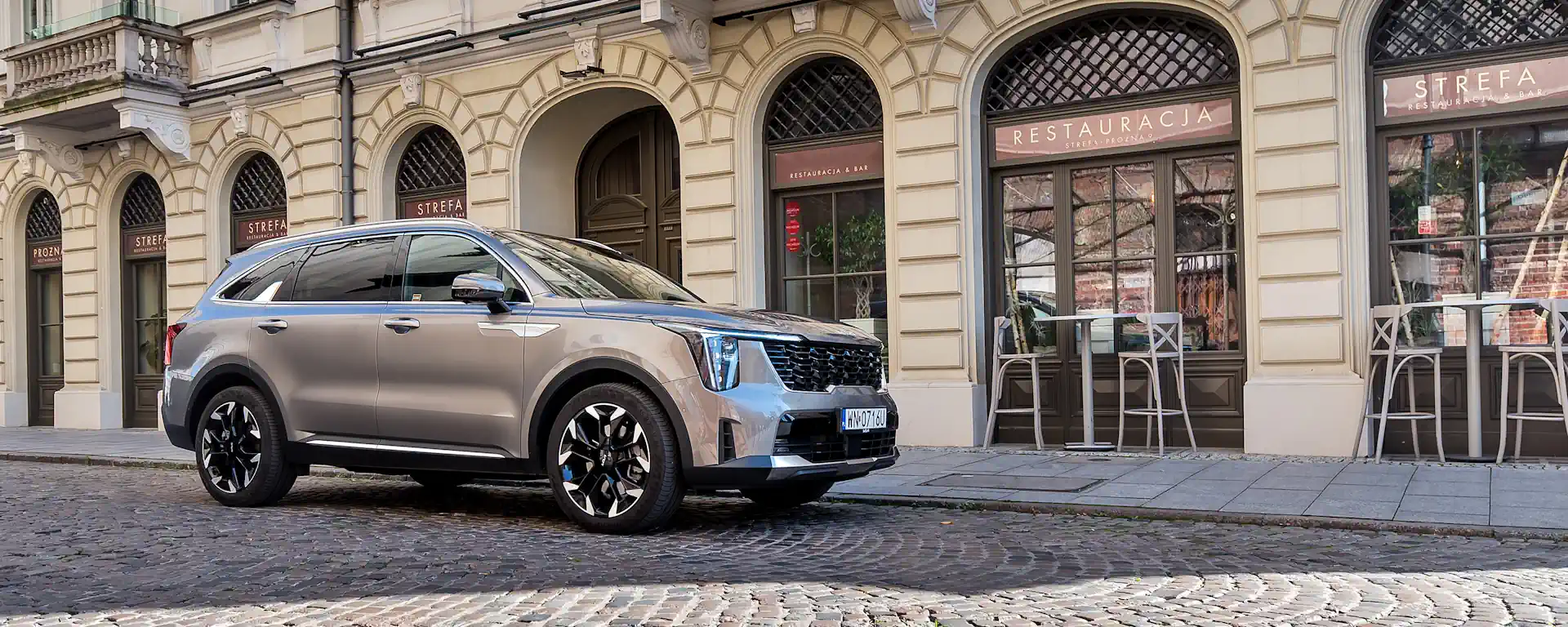 kia sorento adwert 27 Beżowa Kia Sorento stoi przed restauracją, widać przód i prawy bok samochodu