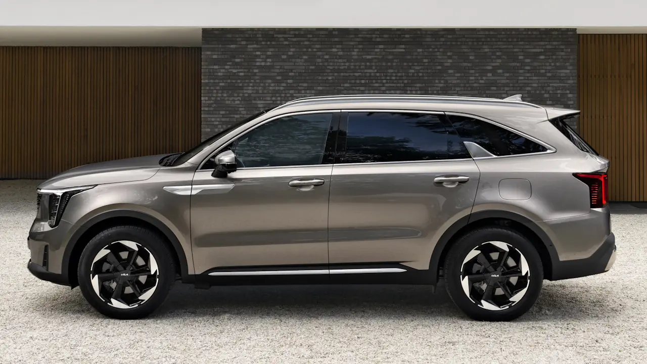 kia sorento adwert 24a Lewy profil beżowej Kii Sorento stojącej przed nowoczesnym budynkiem