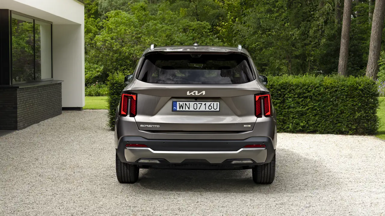 kia sorento adwert 25 Tył beżowej Kii Sorento stojącej przed nowoczesnym budynkiem