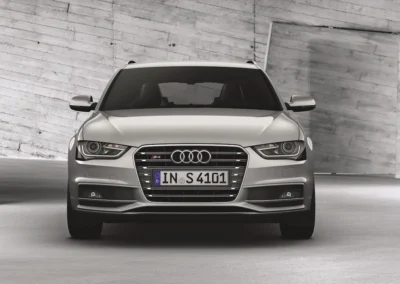 Przód srebrnego Audi A4 B8 stojącego na tle betonowej ściany