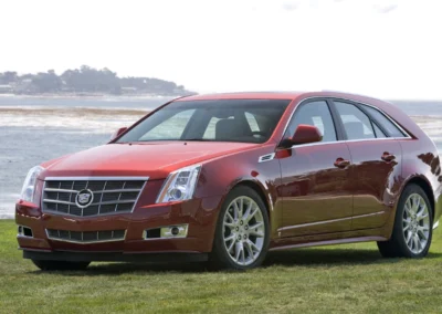 Czerwony Cadillac CTS 2 generacji stoi na tle zatoki, widać przód i lewy bok auta