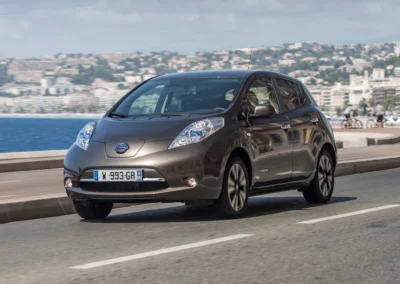Grafitowy Nissan Leaf jedzie na nabrzeżu, widać przód i lewy bok auta