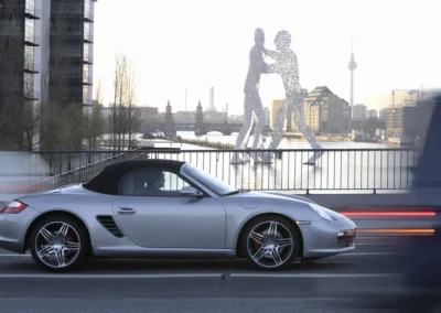 Prawy profil srebrnego Porsche Boxtera 987 jadącego przez most w Berlinie