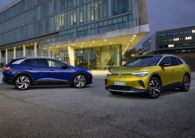 Dwa Volkswageny Id.4 stoją na parkingu, niebieski prawym bokiem, żółty przodem i lewym bokiem