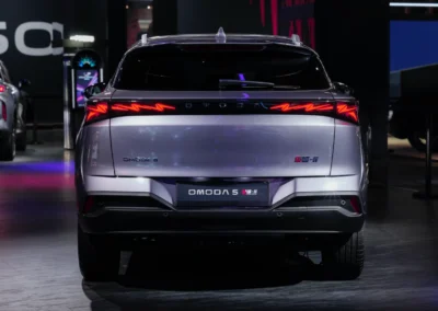 Szara Omoda 5 Next stoi na stoisku podczas salonu samochodowego – widać tył auta.