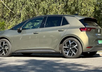 Volkswagen ID.3 Neo stoi na brukowanej drodze – widać tył i lewy bok auta, w tle są drzewa.